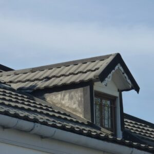 Snow rests on a durable residential roof with metal panels, slate sections, and carefully sealed flashing around a chimney.